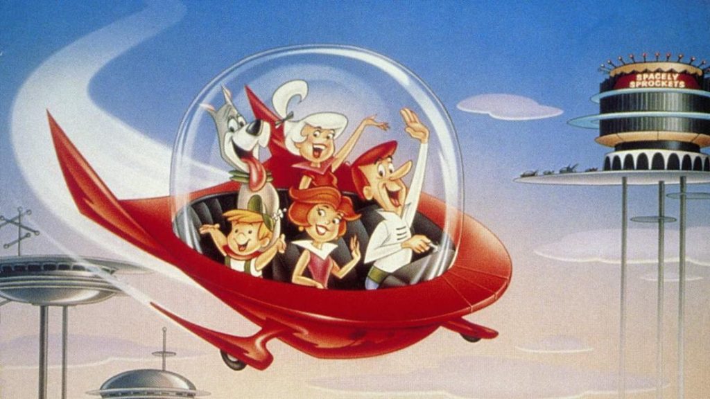 Die Cartoon-Familie der Jetsons (George, Jane, Judy und Elroy) und ihr Hund Astro fliegen in ihrem roten, futuristischen, blasenförmigen Raumschiff durch den hellblauen Himmel. George steuert das Fahrzeug, winkt und lächelt. Jane, Judy und Astro winken ebenfalls und lächeln fröhlich. Die moderne, futuristische Skyline ist im Hintergrund zu sehen, mit Gebäuden auf hohen Stelzen und dem kreisförmigen, mehrstöckigen "Spacely Sprockets"-Gebäude oben rechts.