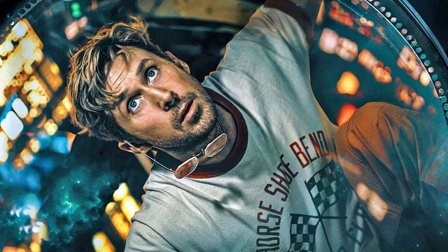 Mann mit überraschtem Blick, T-Shirt mit Aufdruck, Sonnenbrille um den Hals. Verschwommener Hintergrund mit Lichtern und kosmischen Elementen.