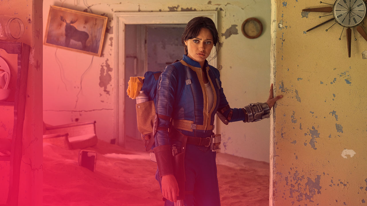 Frau in blauem Overall blickt besorgt in verfallener Sand-Wohnung. Gelbe Wände, Rucksack, Metallarmreif, Elchbild, alte Uhr.