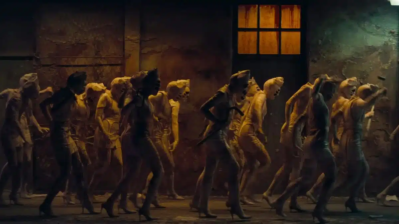 Gruppe von Frauen in Uniformen und High Heels geht in einem dunklen, schmutzigen Korridor mit einem beleuchteten Fenster.