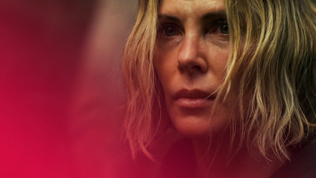 Nahaufnahme einer Frau mit verschwitztem Gesicht und zerzausten blonden Haaren. Ihr Blick ist ernst und entschlossen.