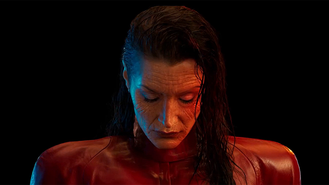 Person mit feuchtem Haar und geschlossenen Augen blickt vor schwarzem Hintergrund herab. Rot-blaues Licht auf rotem Leder.