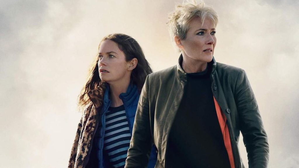 Zwei Frauen blicken mit ernstem Ausdruck nach rechts oben. Eine mit langen braunen Haaren, die andere mit kurzen blonden. Bewölkter Himmel.