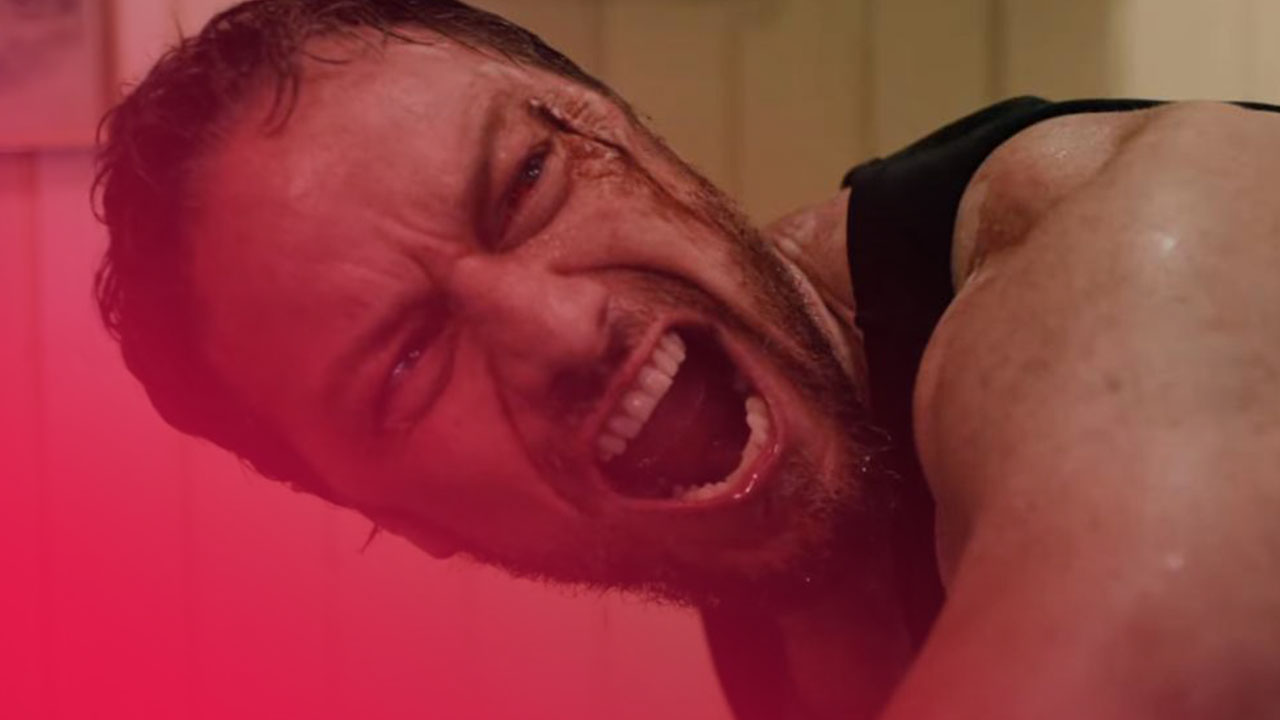 Nahaufnahme eines Mannes mit schmerzverzerrtem, schreiendem Gesicht, Blutspritzern an der Stirn und verschwitzter Haut.