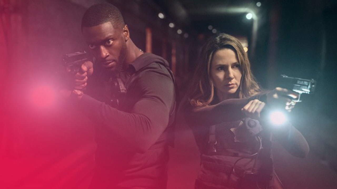 Zwei Einsatzkräfte mit gezogenen Pistolen und hellen Taschenlampen in einem dunklen Tunnel, angespannte Atmosphäre.