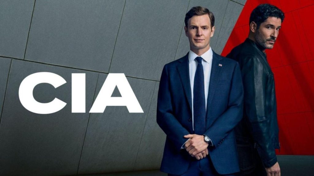 Zwei Männer, einer im Anzug, einer in Lederjacke, vor grau-rotem Hintergrund mit dem großen weißen Schriftzug „CIA“.