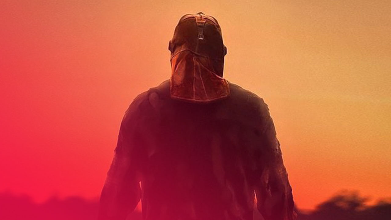 Silhouette einer kräftigen Gestalt mit einer Maske vor einem orangefarbenen, dämmrigen Abendhimmel.