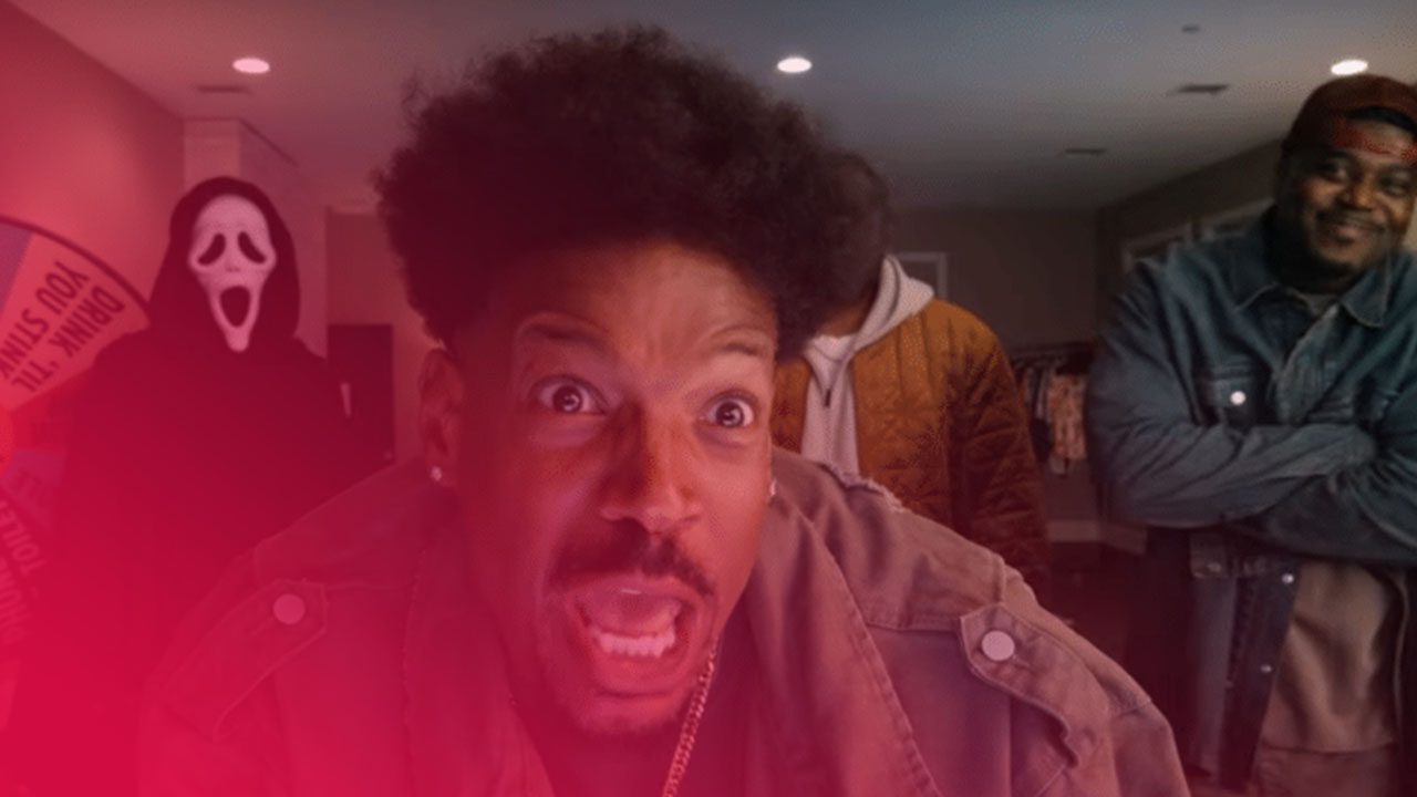 Drei Männer und eine Person in Ghostface-Maske vor einem Glücksrad; der Mann im Vordergrund schaut erschrocken.