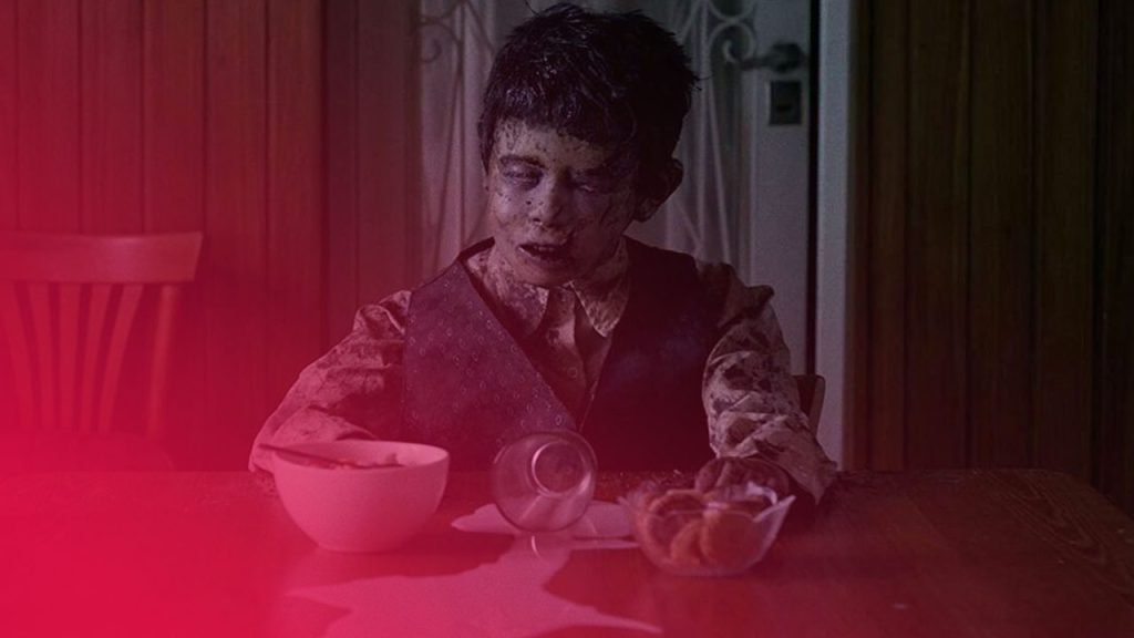 Ein Junge mit schmutzigem Gesicht und Kleidung sitzt an einem Holztisch, vor ihm eine verschüttete Milch, eine Schüssel und ein umgekipptes Glas.