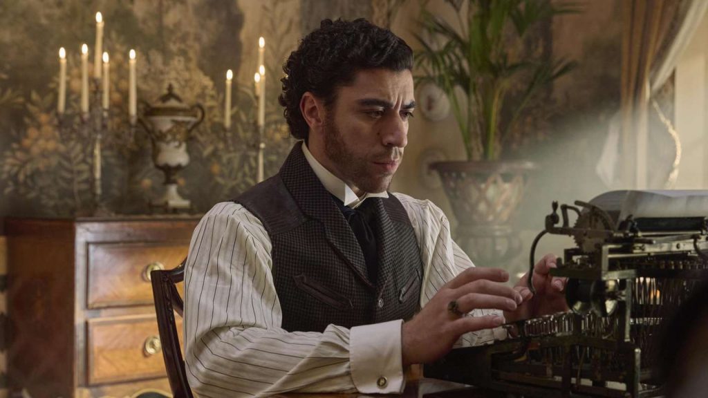 Ein Mann in historischer Kleidung sitzt konzentriert an einer alten Schreibmaschine in einem eleganten, kerzenbeleuchteten Raum.
