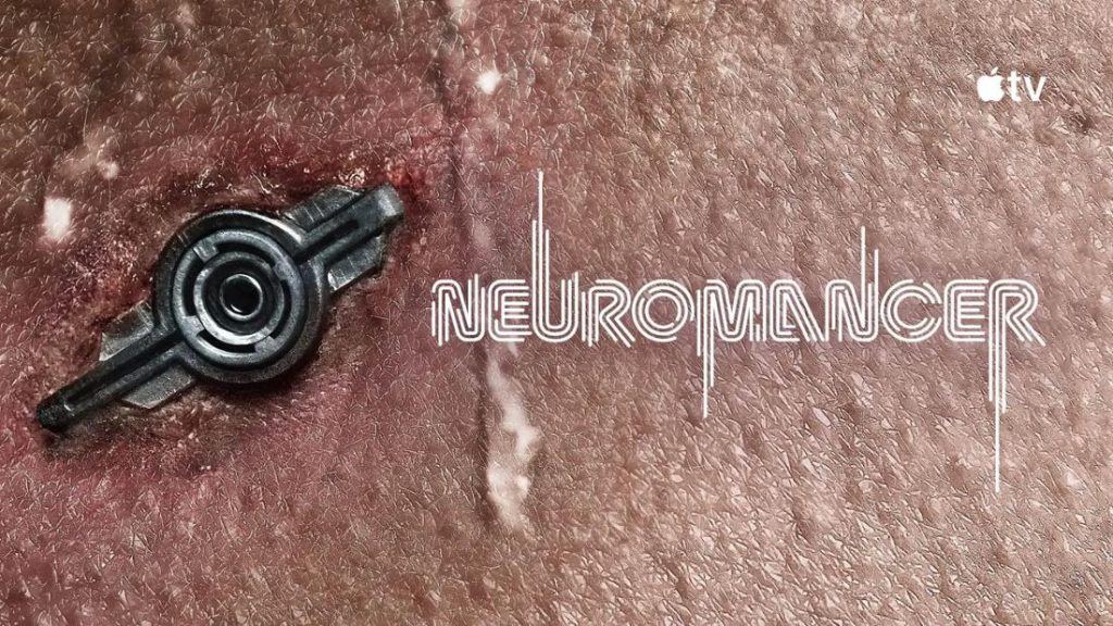 Eine Nahaufnahme zeigt menschliche Haut mit einer Narbe und einem kleinen, schwarzen, futuristischen Implantat. Rechts daneben steht in weißer, stilisierter Schrift der Titel „NEUROMANCER“. Oben rechts ist das Logo von Apple TV zu sehen. Die Szene vermittelt eine düstere, technologische Stimmung.