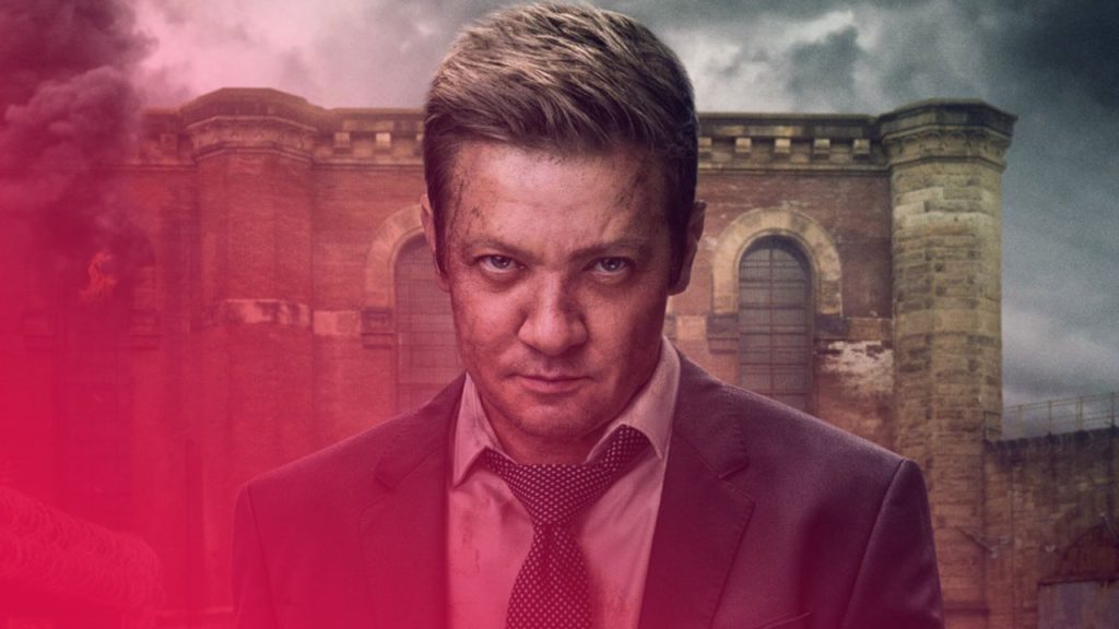 Nahaufnahme eines Mannes, gespielt von Jeremy Renner, mit ernstem und intensivem Blick direkt in die Kamera. Er hat kurze, braune Haare und sein Gesicht ist mit Schmutz und Kratzern bedeckt. Er trägt einen dunklen Anzug, ein weißes Hemd und eine gepunktete Krawatte. Im Hintergrund ist ein großes, altes, braunes Ziegelsteingebäude zu sehen, das teilweise von dicken Rauchwolken umgeben ist, die in den grauen, bedeckten Himmel aufsteigen. Eine Flamme ist an der Seite des Gebäudes zu sehen.
