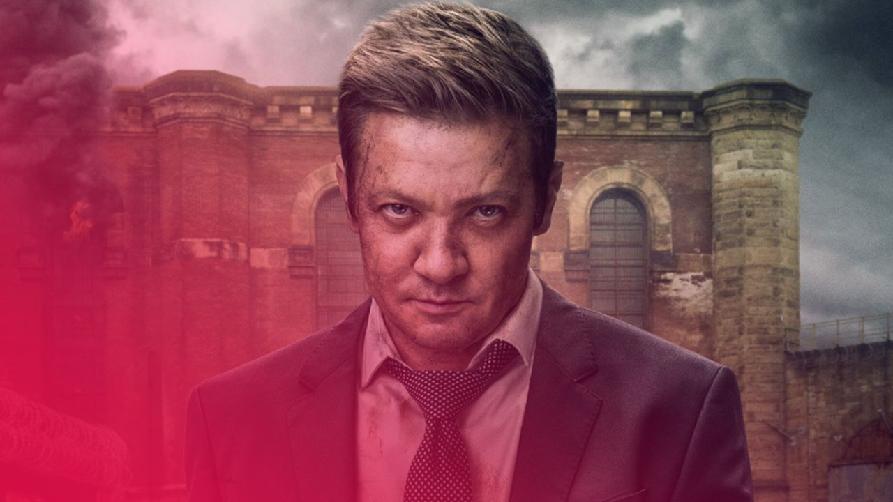 Nahaufnahme eines Mannes, gespielt von Jeremy Renner, mit ernstem und intensivem Blick direkt in die Kamera. Er hat kurze, braune Haare und sein Gesicht ist mit Schmutz und Kratzern bedeckt. Er trägt einen dunklen Anzug, ein weißes Hemd und eine gepunktete Krawatte. Im Hintergrund ist ein großes, altes, braunes Ziegelsteingebäude zu sehen, das teilweise von dicken Rauchwolken umgeben ist, die in den grauen, bedeckten Himmel aufsteigen. Eine Flamme ist an der Seite des Gebäudes zu sehen.